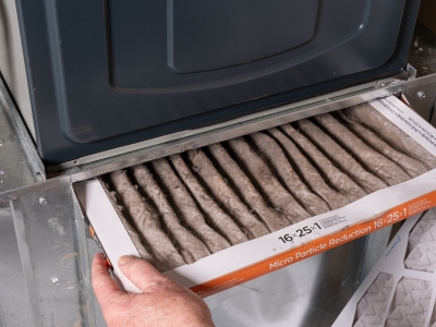 Furnace filter being replaced in HVAC system, emphasizing importance of regular maintenance to prevent overheating and ensure proper airflow.