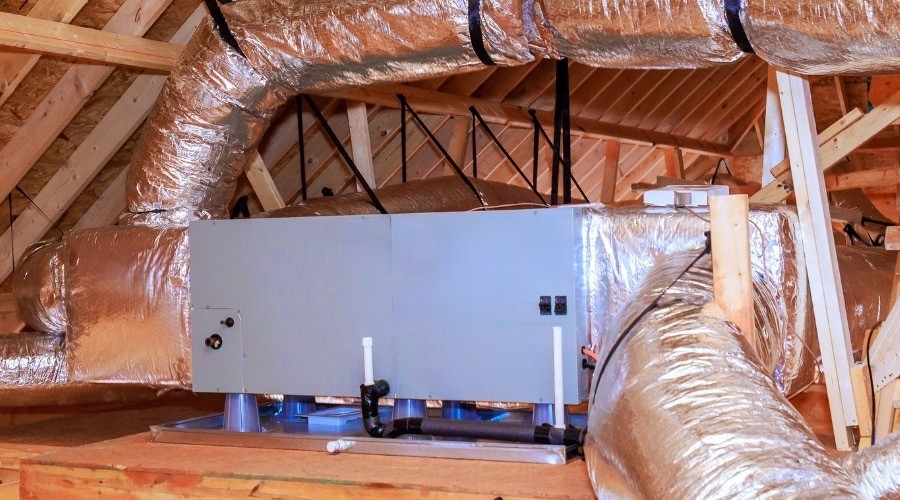 Air handler unit in attic with ductwork and insulation